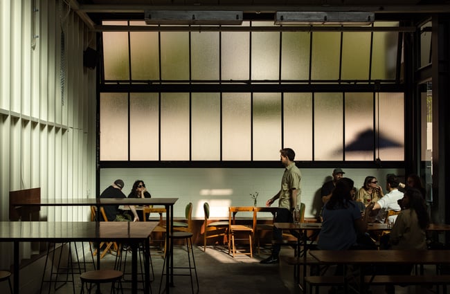 Customers dining inside a darkly lit bar space.