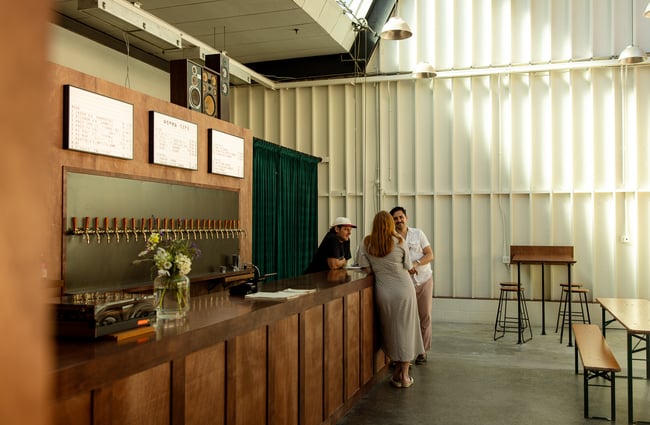 A man and woman chatting to a staff member at the counter at Norma Taps in Auckland.