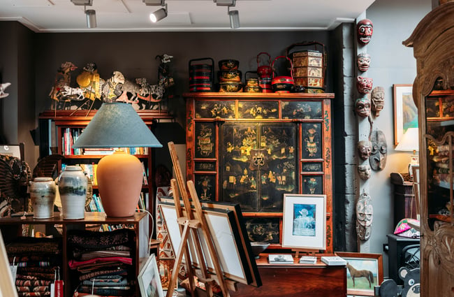 Low-lit room full of antiques and a big wardrobe with intricate Japanese-inspired paintings over it