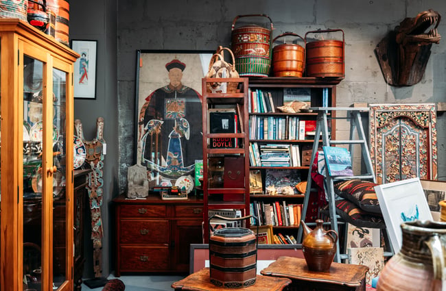 Shelf of old books next to a wooden dragon head and a large artwork of an emperor