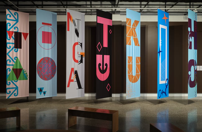 Large colourful flags on display inside an art gallery.