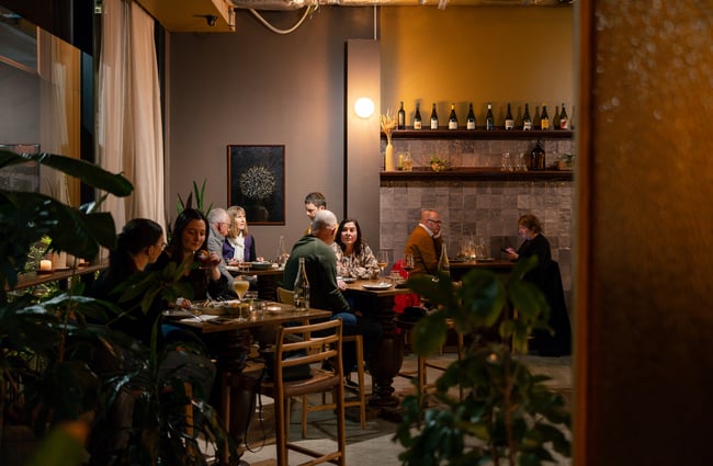 Customers sitting at tables in a dimly lit dining room at Odeon.
