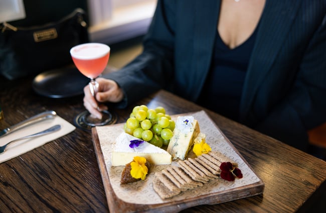Customer enjoying a pink cocktail and cheeseboard at OGB