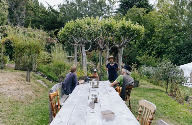Three people chatting outside at Okuti Garden in Little River.