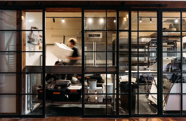 A staff member working in the bakery behind a glass wall.