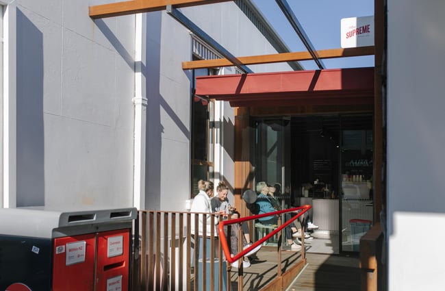 People dining outside a tiny cafe on a sunny day.