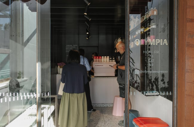 People lining up inside a small cafe.