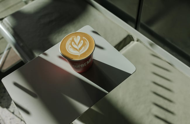 A close up of a coffee on a small table in the sunshine.