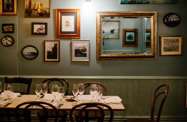 Table by photo frames on wall.