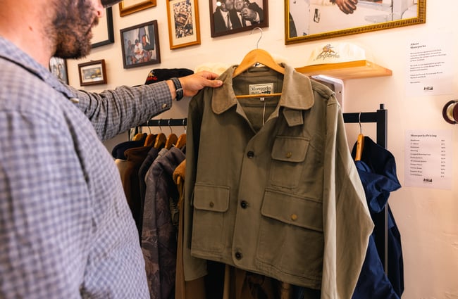 Man holding up Moreporks Jacket at Outdoors Society in Auckland