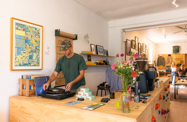 Man playing vinyl on record player at Outdoors Society in Auckland