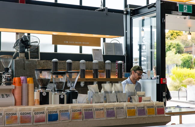 Barista behind the counter and coffees on display at Ozone Coffee.