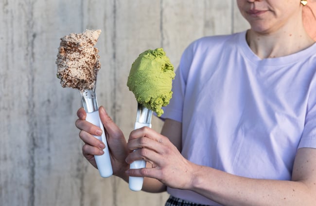 Shop assistant holding up spoons with different scoops of gelato from Paleta Gelateria.