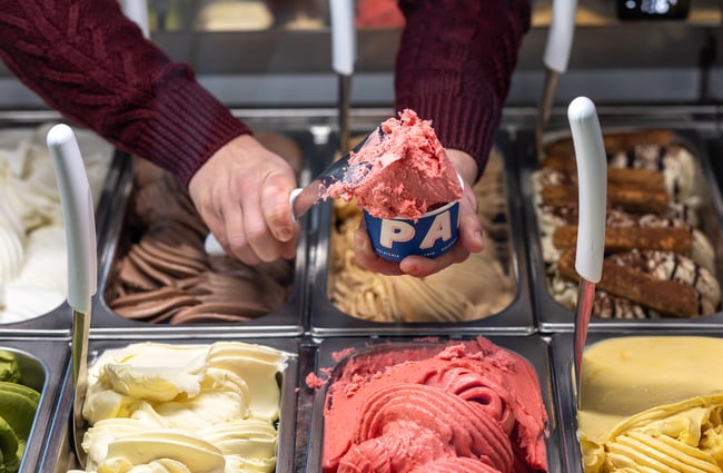 Shop assistant scooping colourful gelato into a cup at Paleta Gelateria.