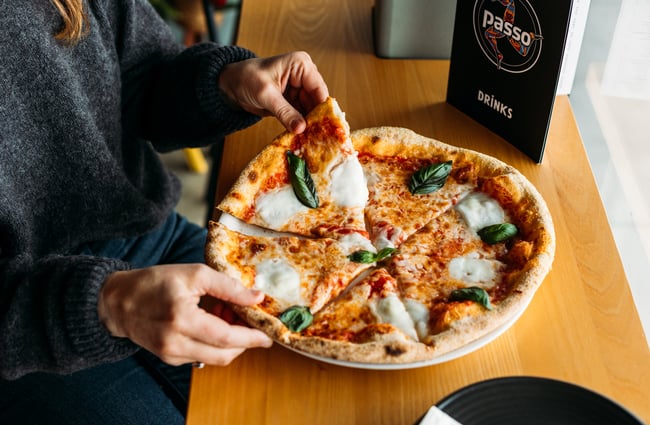 A woman sitting in front of a pizza.