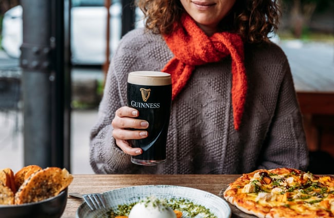Customer sitting at a table with a pint of Guiness and plates of food in front of them at Paulina's Bar.