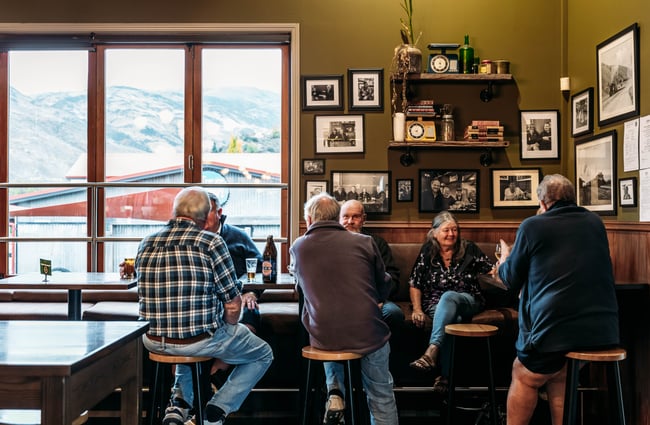 Group of customers sitting at a table drinking beers and talking at Paulina's Bar.