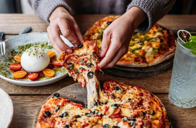 Customer pulling out a piece of pizza at Paulina's Bar.