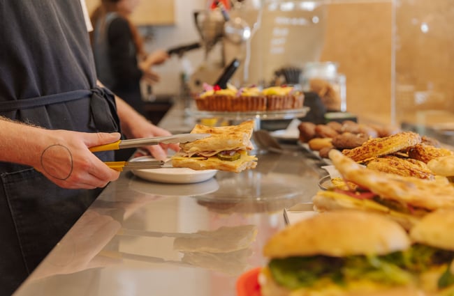 Staff member serving up a sandwich at Peaches.