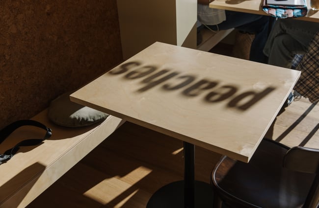 Peaches signage reflecting on the table as a shadow at Peaches.