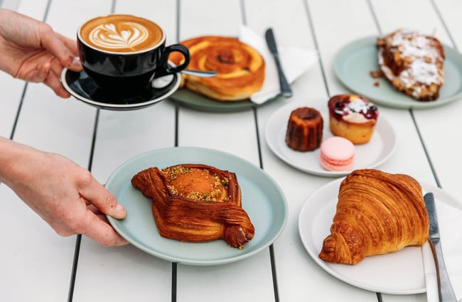 A staff member places a coffee and pastries on the table at Pembroke Pâtisserie, Wānaka.