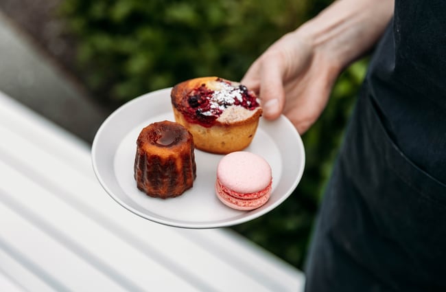 Staff member holding a plate of three sweet treats at Pembroke Pâtisserie.