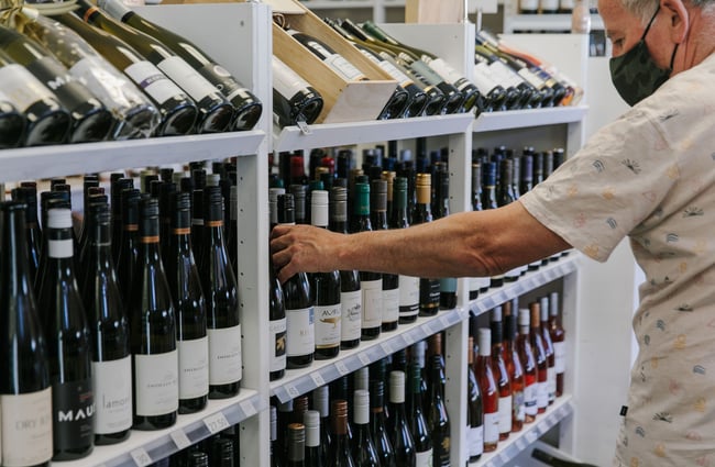Man choosing a bottle of wine from Pembroke Wines & Spirits, Wānaka.