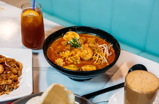 Bowl of curry on the table with a drink next to it at Penang Street Food.