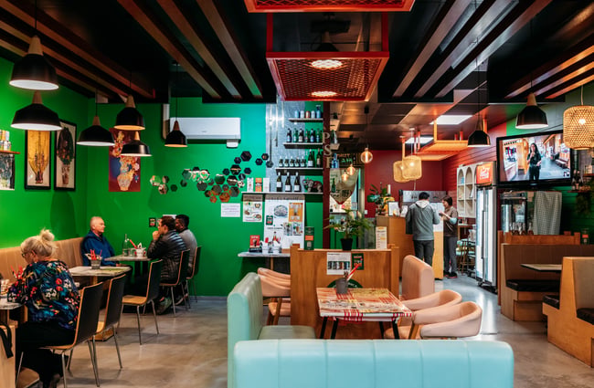 Customers seated at tables in the dining room with green walls behind them at Penang Street Food.