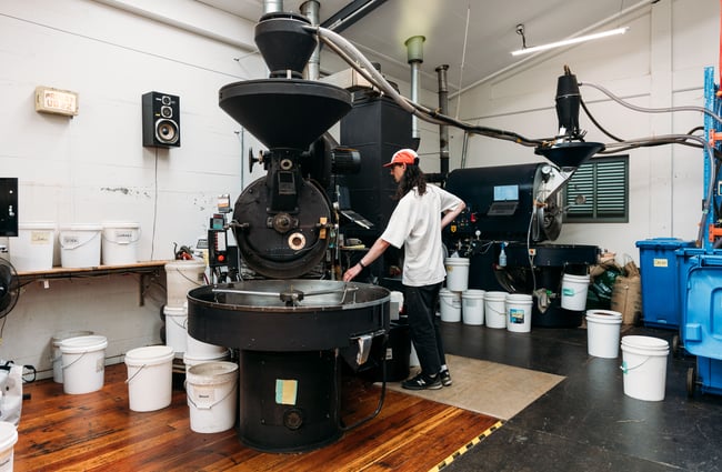 A man roasting at a coffee roasting machine.