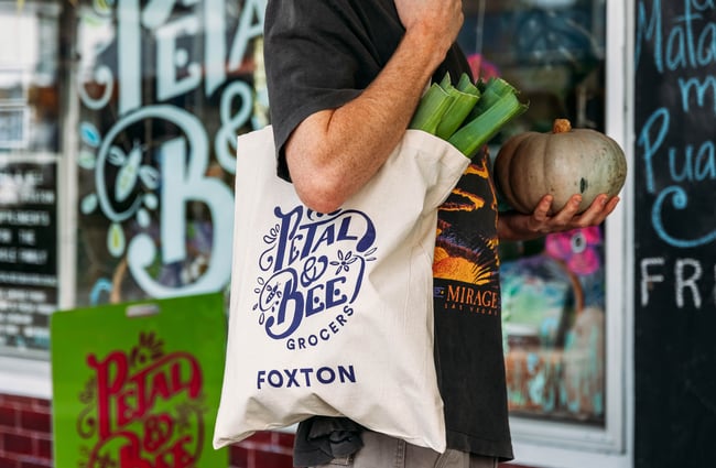Customer with a shop tote bag full of their groceries outside Petal Bee Grocers.