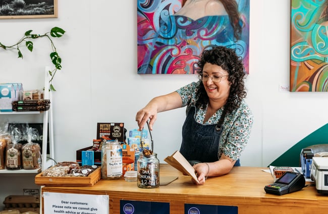 Shop owner behind the front counter at Petal Bee Grocers.