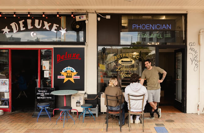 Customers sitting at a table outside the front door of Phoenician Falafel.