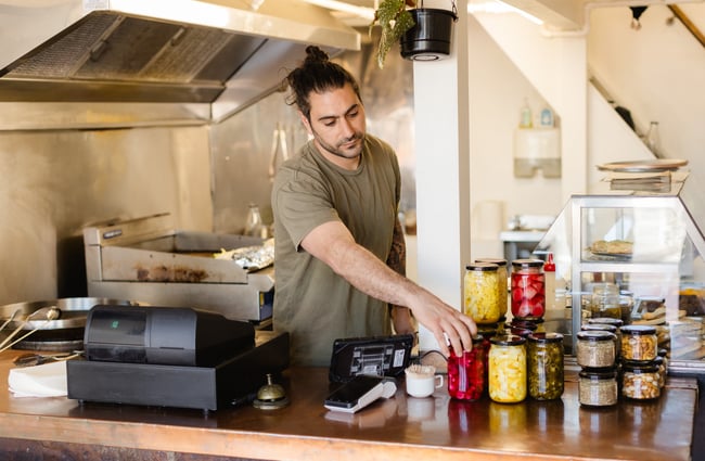 Chef in the kitchen holding a jar at Phoenician Falafel.