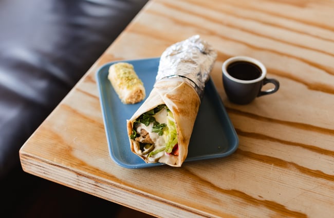 Wrap and a cup of coffee on the table at Phoenician Falafel.
