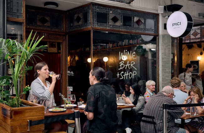 Two women drinking wine together outside Pici in Auckland