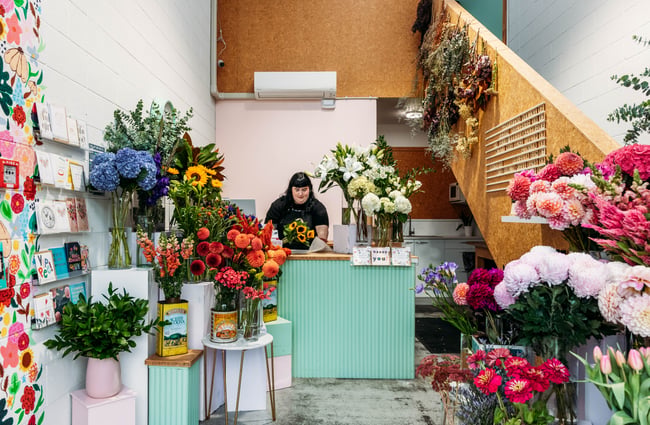 A woman behind a counter at a flower shop.
