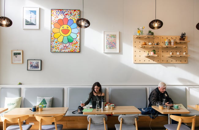 Two people sitting in a brightly lit cafe.