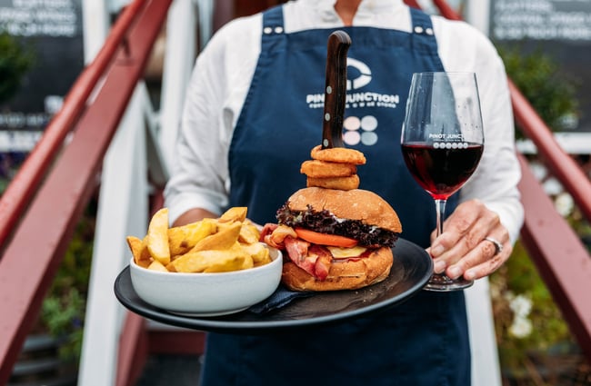 Glass of wine and plate of burger and fries at Pinot Junction.
