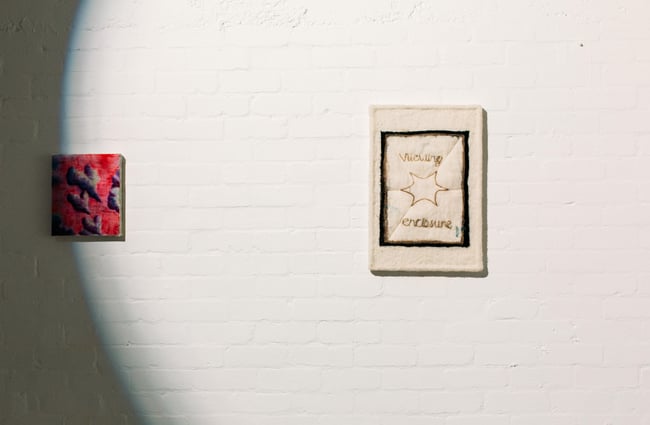A close up of two works of art on a wall.