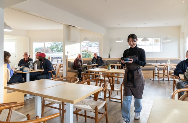 Barista carrying a coffee to a customer at Poca Poca.