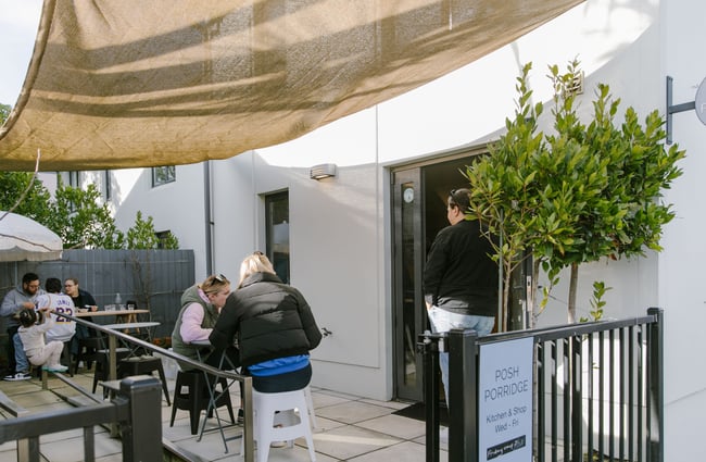 Courtyard seating with shade sail at Posh Porridge.