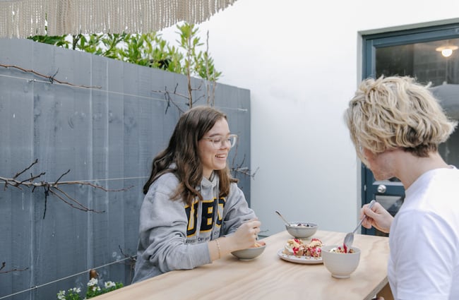 Two women sitting outside eating porridge at Posh Porridge.