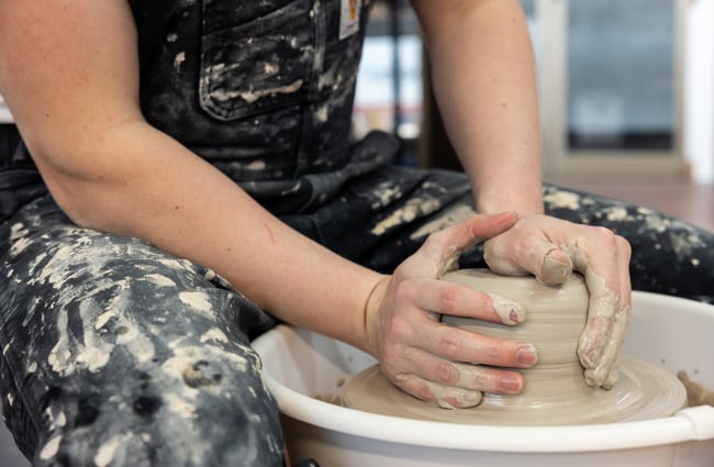 A close up of a potter working with a pottery wheel at Pottery Capital.