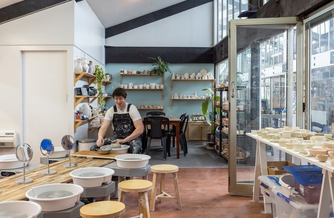 A ceramicist is sitting at a pottery wheel station in Pottery Capital.
