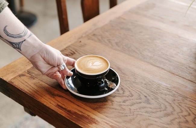 Close up of a flat white being put down on a table.