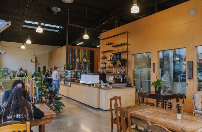 Wide view of the cafe space, customers at the counter and customers sitting at tables at Prima Roastery.