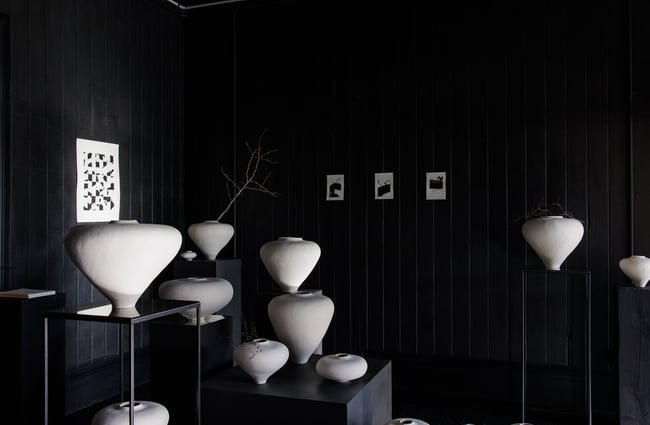 White vases on display in a black room.