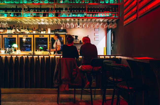 Long bar with two people drinking.