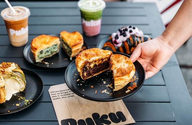 Someone placing steak and cheese pie down on table at Puku Pies in Petone